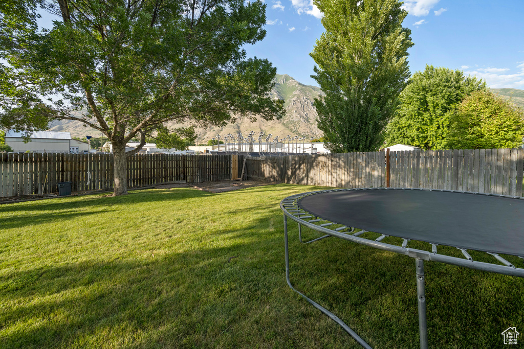 Fenced backyard featuring a trampoline and a mountain view