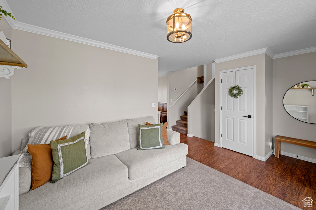 Unfurnished living room with wood finished floors, a chandelier, stairs, and ornamental molding