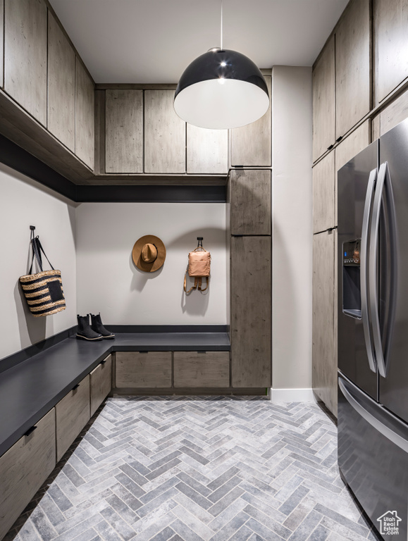 Interior space featuring stainless steel refrigerator with ice dispenser, brick flooring, and dark countertops