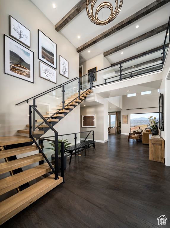Staircase featuring wood finished floors, beam ceiling, a towering ceiling, and recessed lighting