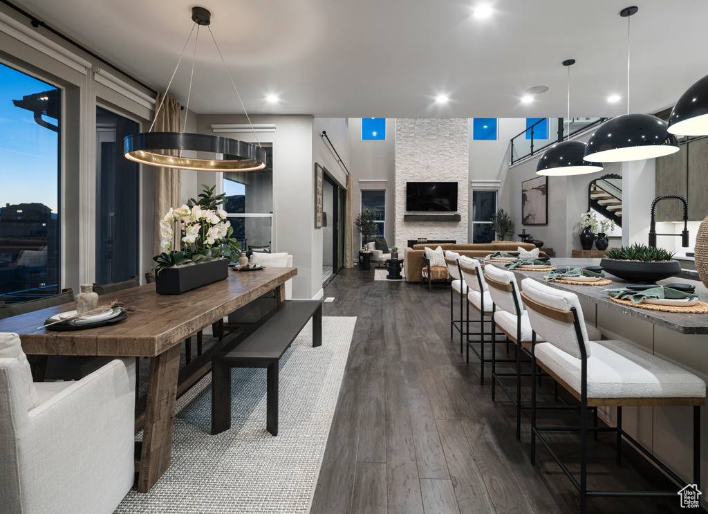 Dining room with dark wood-style flooring, recessed lighting, and stairs