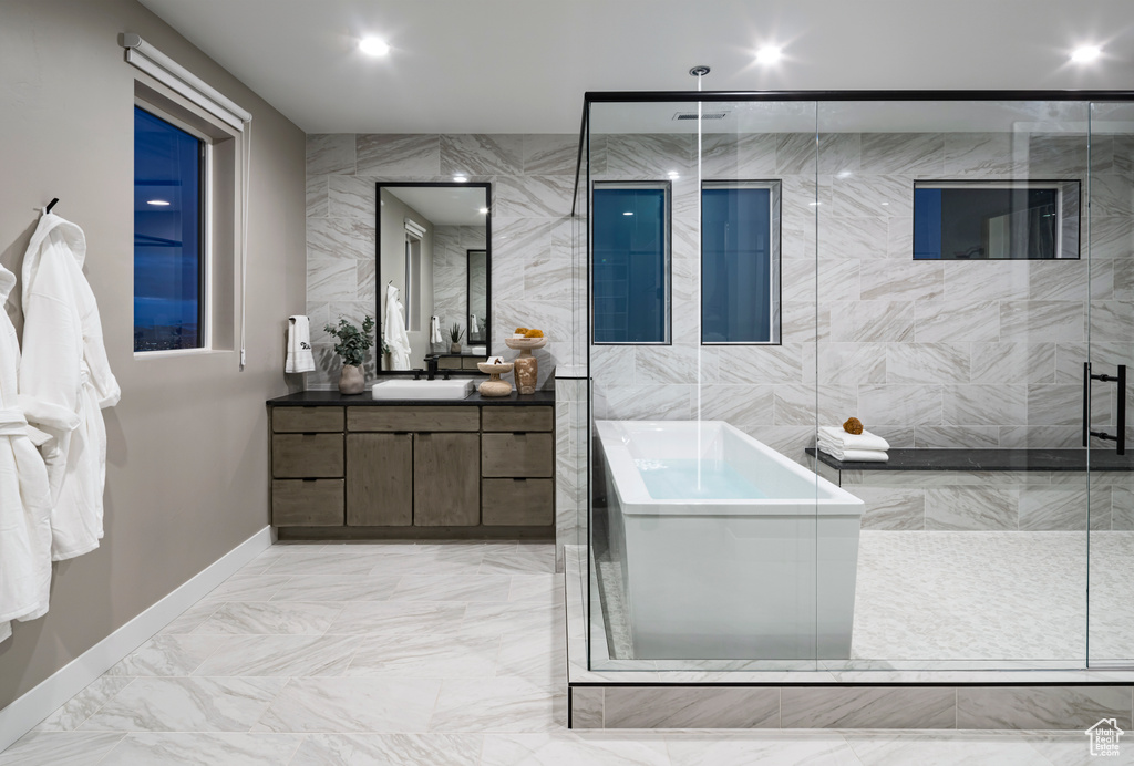 Full bath featuring vanity, a freestanding bath, marble finish floors, and a stall shower