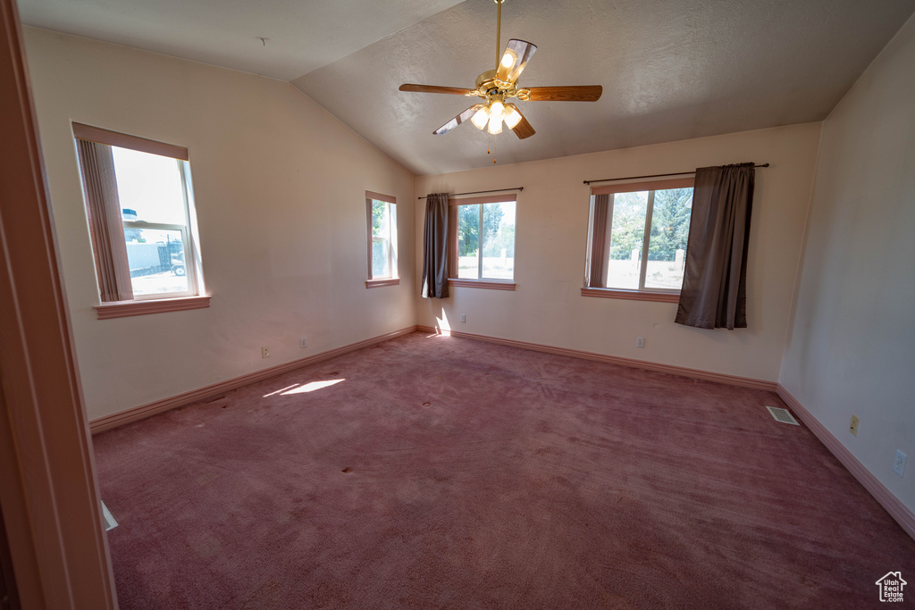 Spare room with lofted ceiling, ceiling fan, and carpet floors