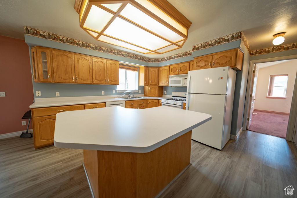 Kitchen featuring white appliances, light wood-style flooring, light countertops, and glass insert cabinets