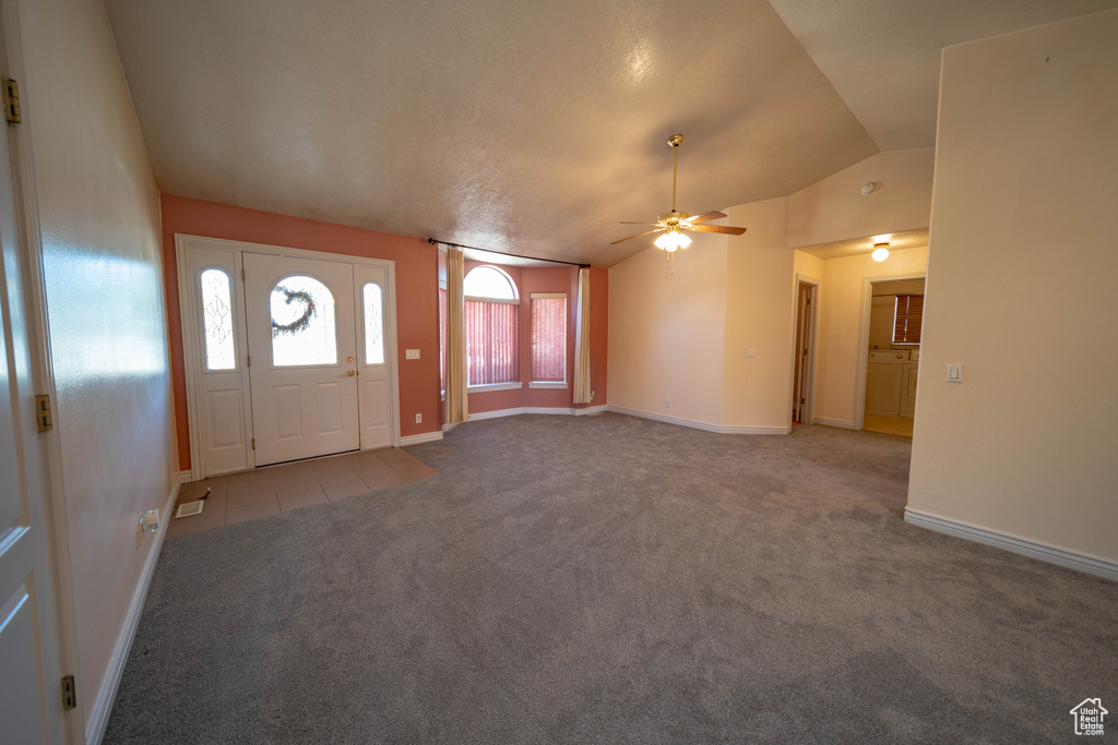 Tiled foyer entrance featuring carpet flooring, vaulted ceiling, and a ceiling fan