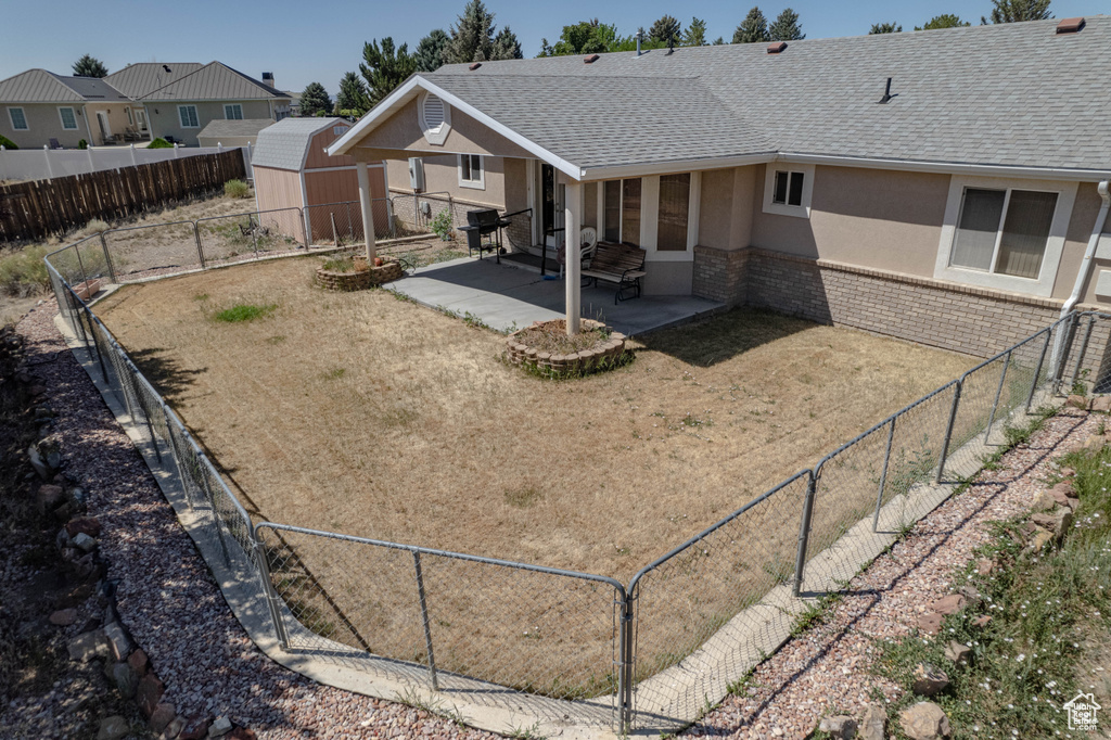 Rear view of property with stucco siding, a patio, roof with shingles, and a fenced backyard