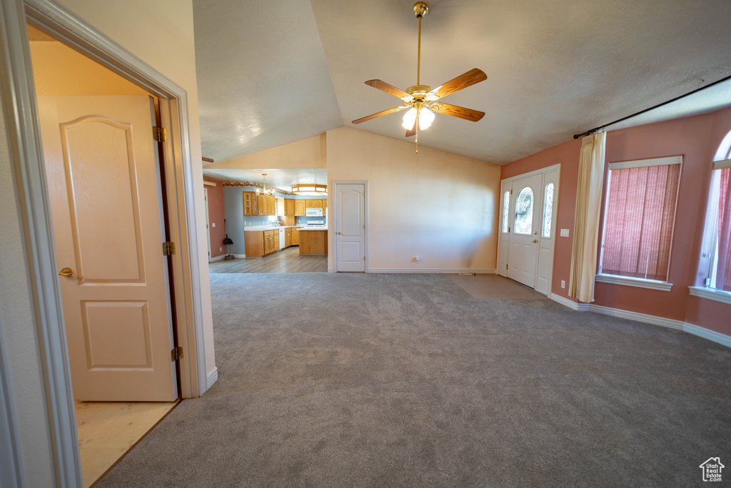 Unfurnished living room featuring carpet floors, ceiling fan, and lofted ceiling