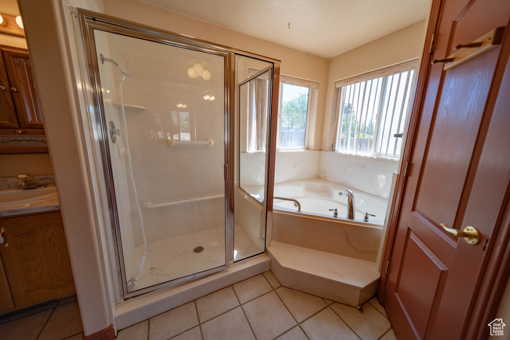 Full bathroom featuring a bath, a stall shower, tile patterned floors, and vanity