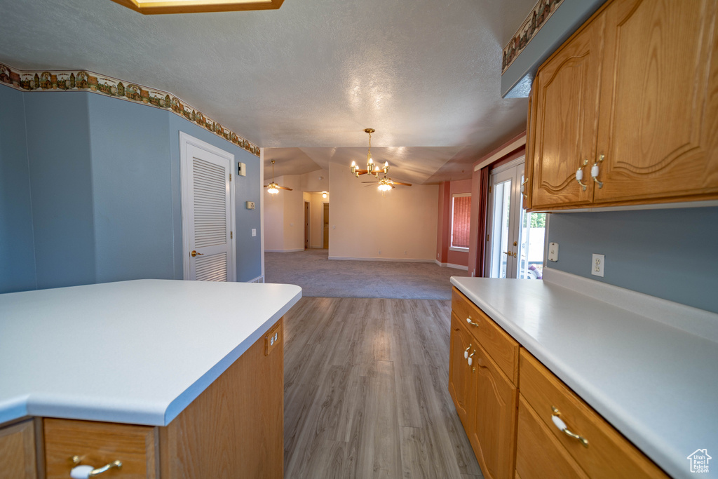 Kitchen with a chandelier, light countertops, open floor plan, lofted ceiling, and a textured ceiling