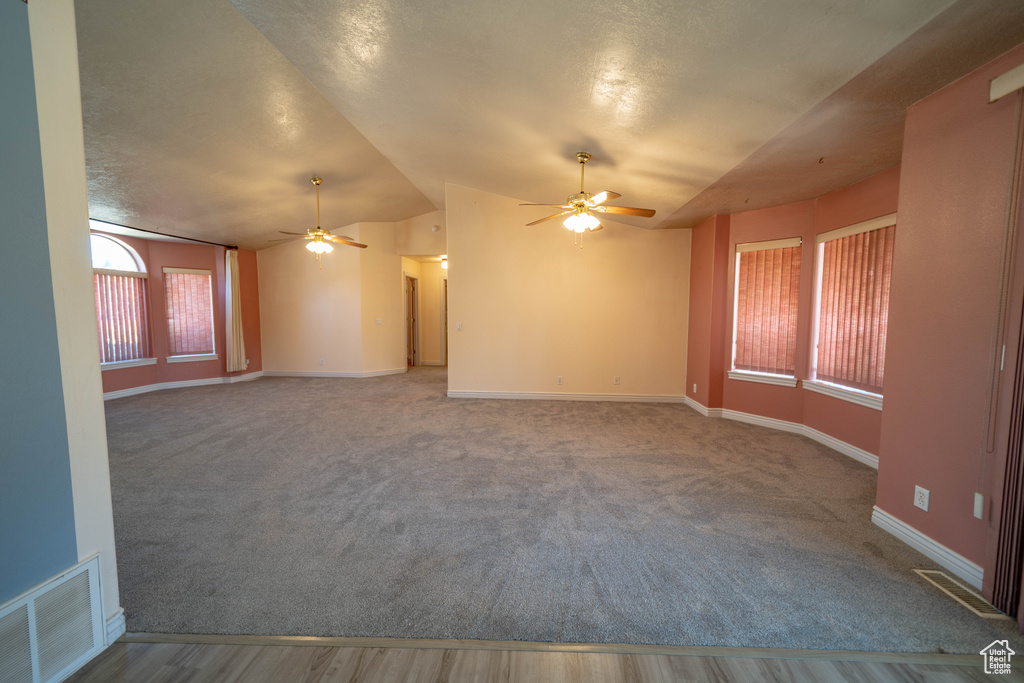 Unfurnished room featuring a ceiling fan, vaulted ceiling, and carpet flooring