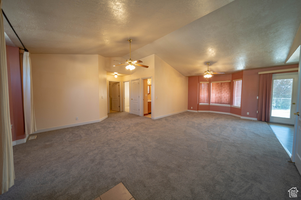 Unfurnished living room featuring ceiling fan, carpet flooring, vaulted ceiling, and a textured ceiling
