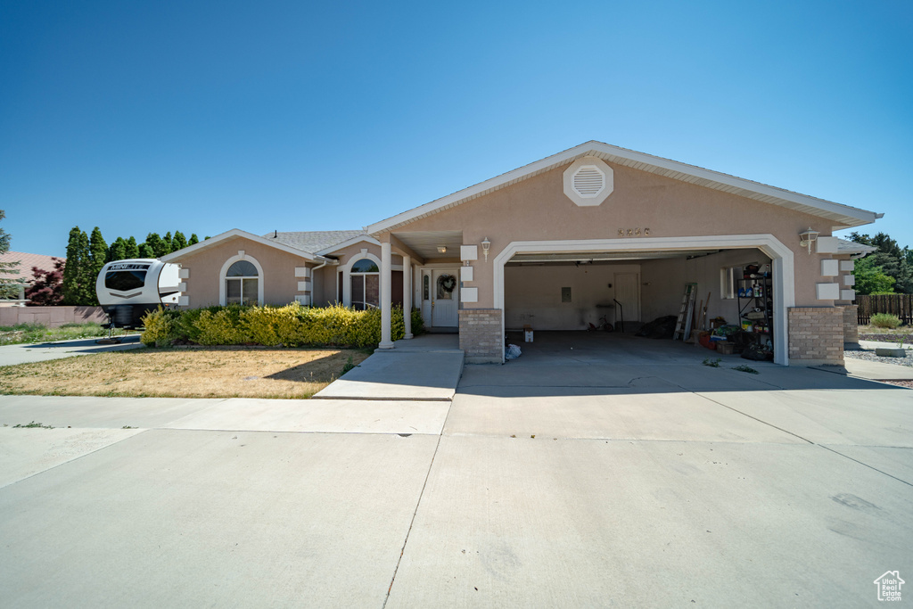 Ranch-style home with a garage, stucco siding, driveway, and brick siding