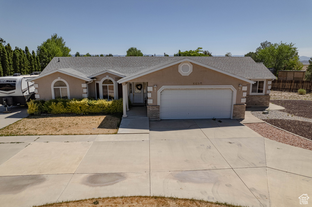 Single story home with concrete driveway, a garage, brick siding, stucco siding, and roof with shingles