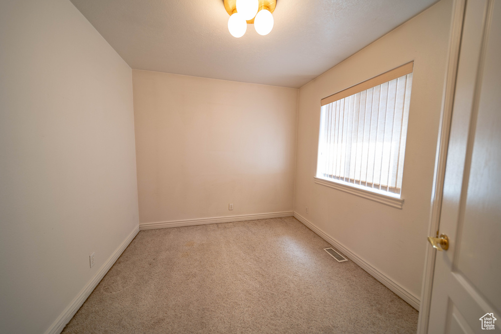 Empty room with light colored carpet and baseboards