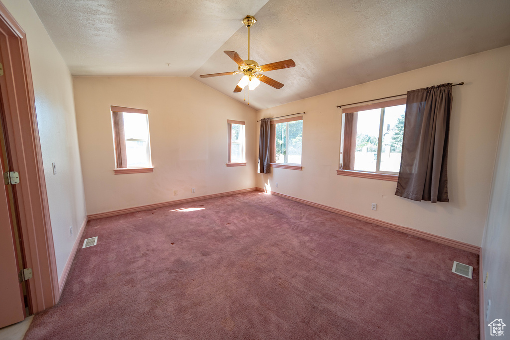 Empty room featuring carpet floors, vaulted ceiling, and ceiling fan