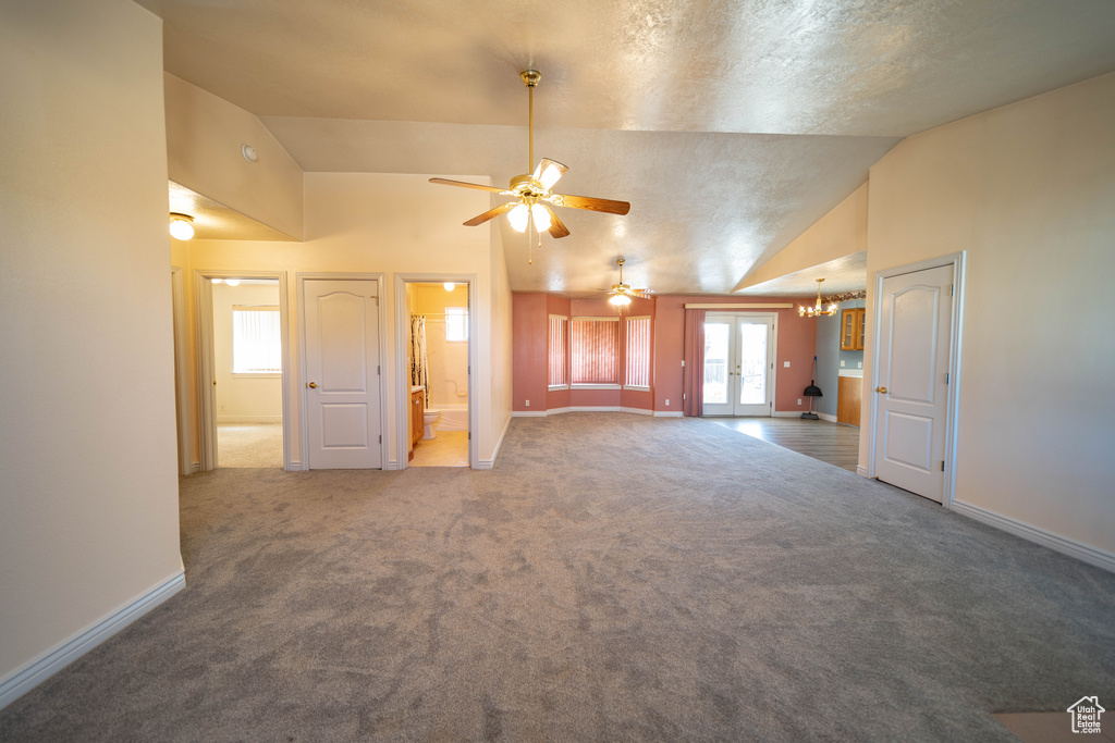Unfurnished living room with ceiling fan, carpet, vaulted ceiling, and a chandelier