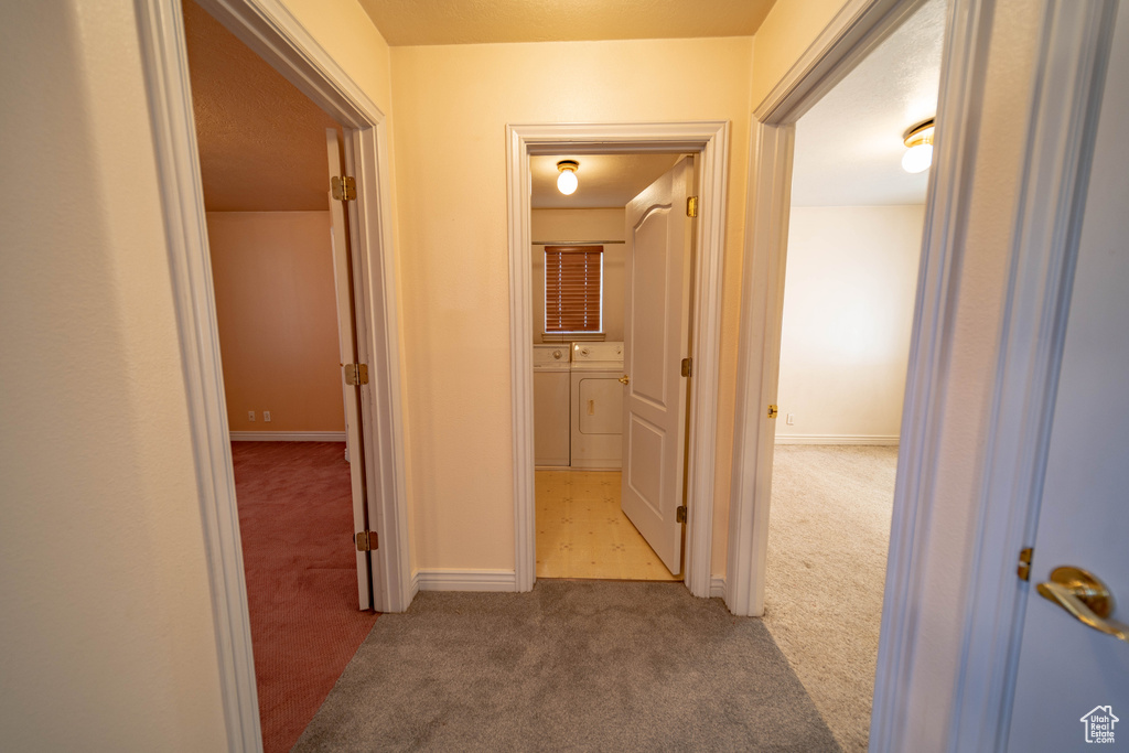 Hall featuring separate washer and dryer and carpet