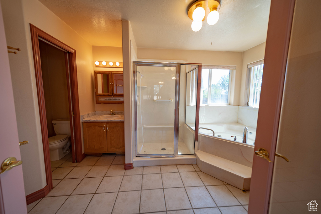 Full bathroom featuring vanity, a bath, a shower stall, tile patterned flooring, and a textured ceiling