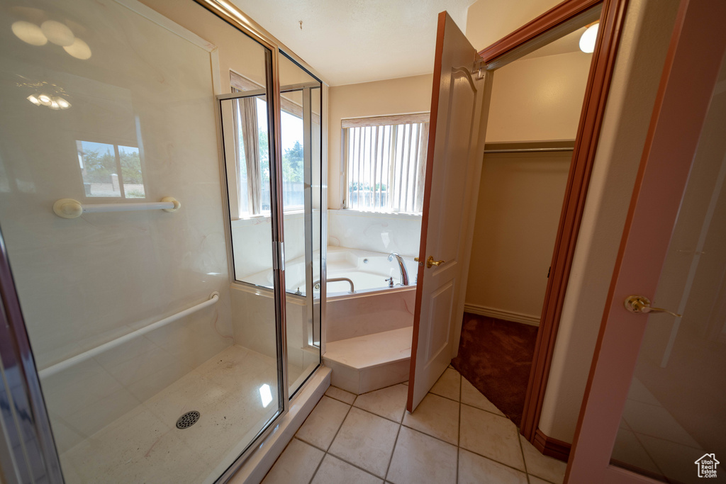 Full bathroom with a shower stall, tile patterned flooring, a garden tub, and a walk in closet