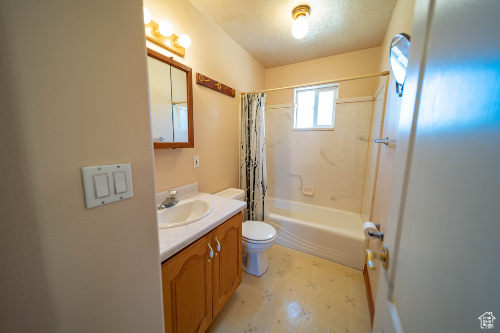 Full bath featuring vanity, shower / bathtub combination with curtain, a textured ceiling, and tile patterned floors