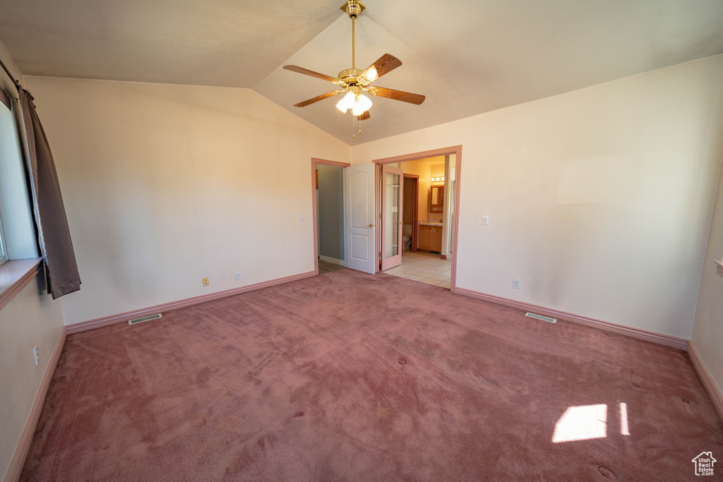 Unfurnished bedroom featuring lofted ceiling, carpet flooring, ensuite bath, and ceiling fan