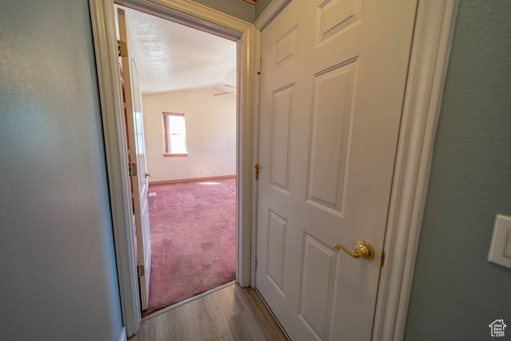 Corridor with vaulted ceiling and wood finished floors