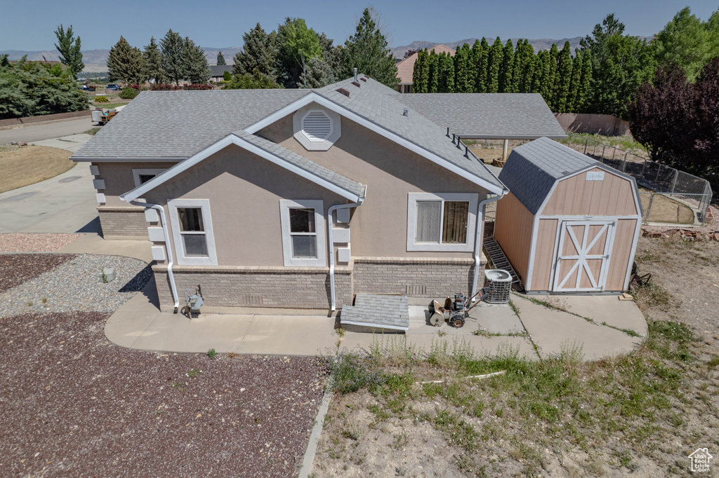 Back of house featuring a storage unit and brick siding