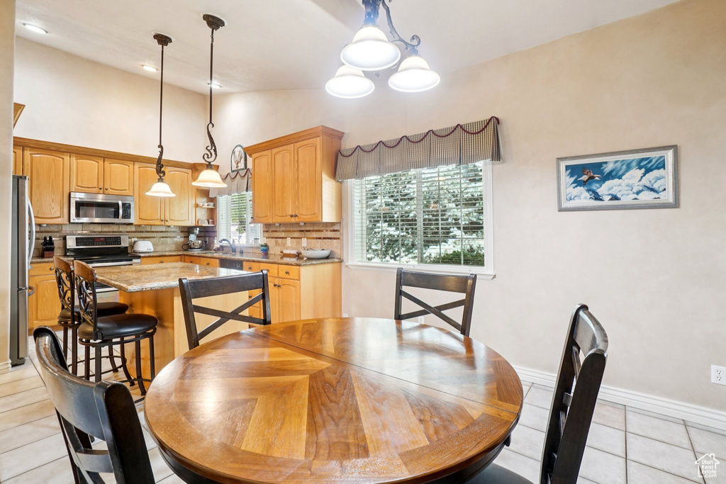 Dining room with light tile patterned floors, vaulted ceiling, and a chandelier