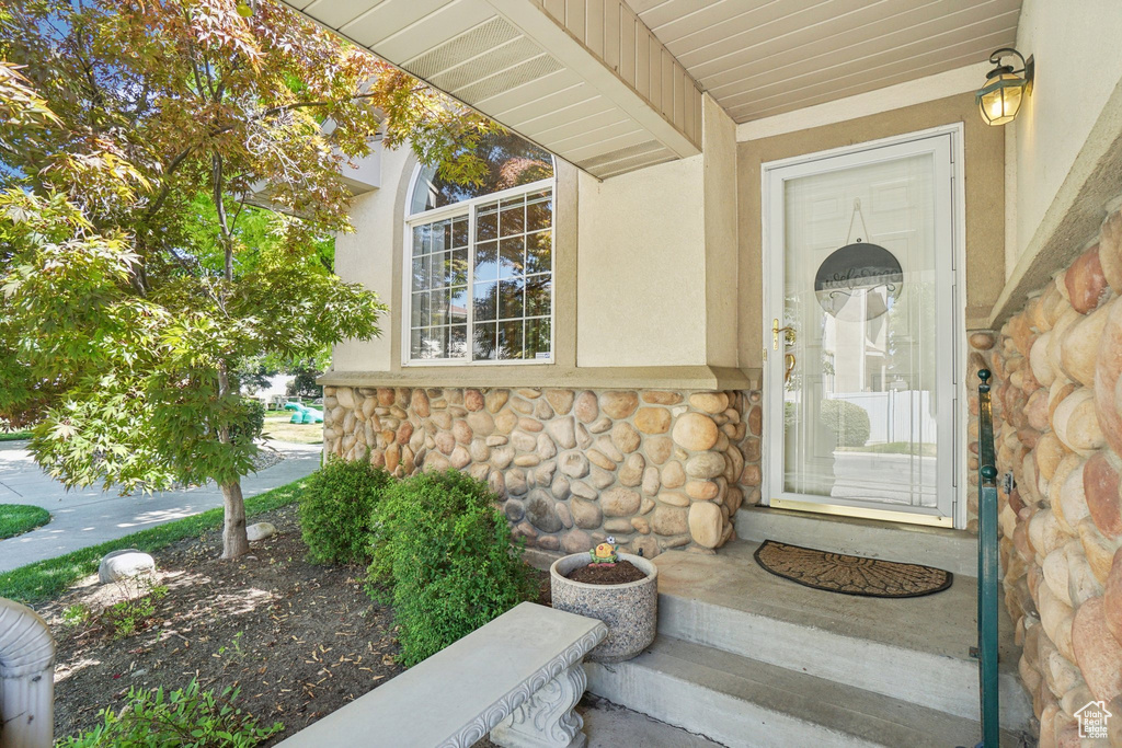 Doorway to property featuring stone siding and stucco siding