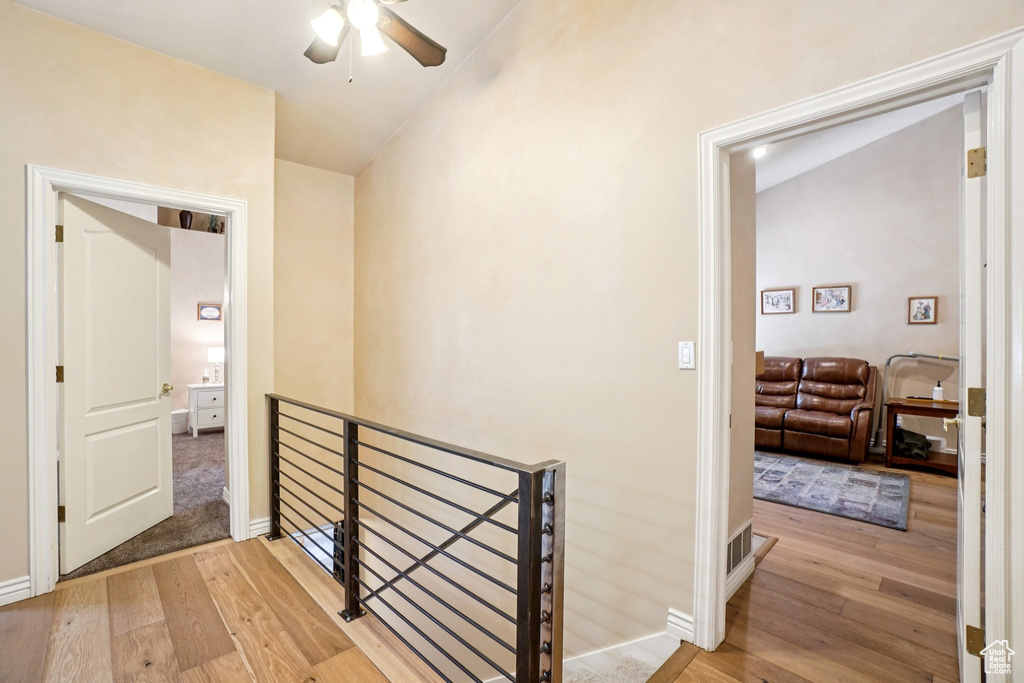 Hallway featuring an upstairs landing, hardwood / wood-style flooring, and vaulted ceiling