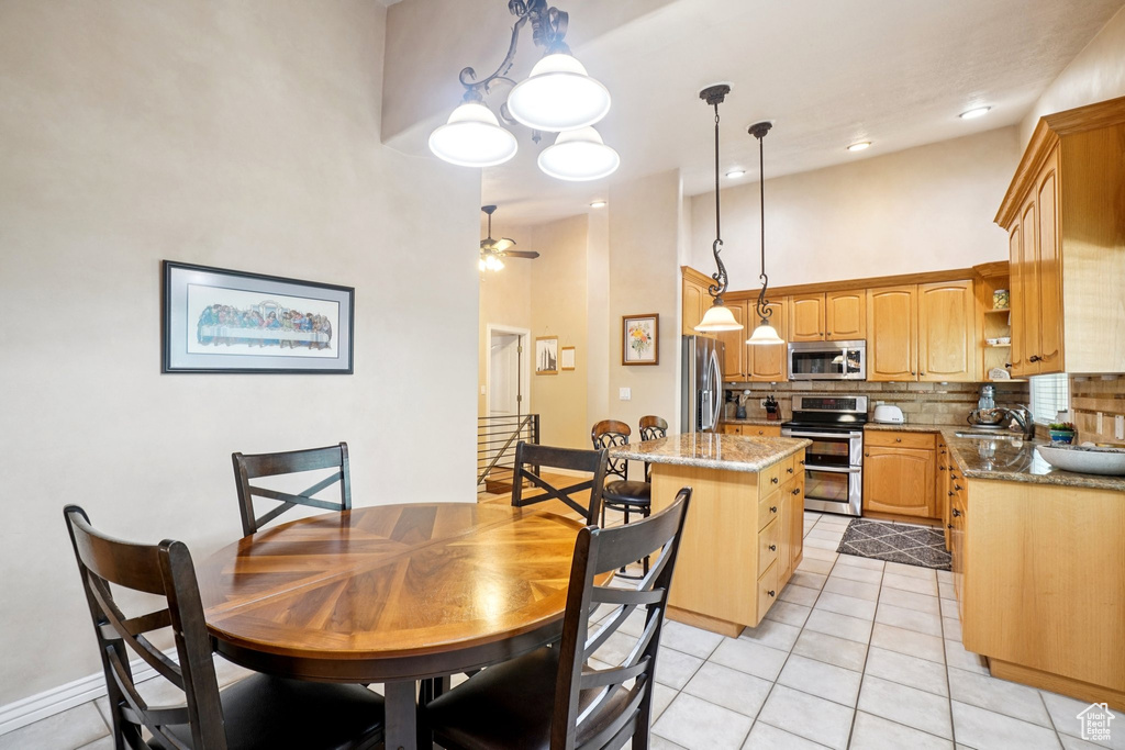 Dining space featuring a towering ceiling, light tile patterned flooring, and a ceiling fan