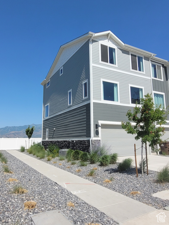 View of side of home featuring a garage, a mountain view, stone siding, and concrete driveway