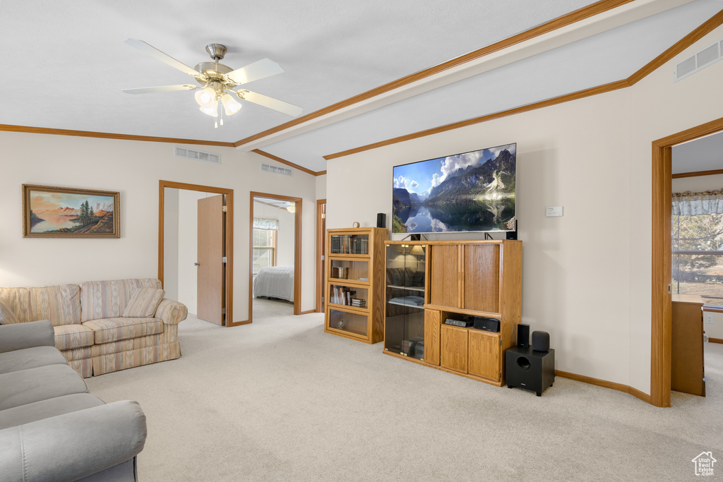 Living area with vaulted ceiling, carpet, a ceiling fan, and crown molding
