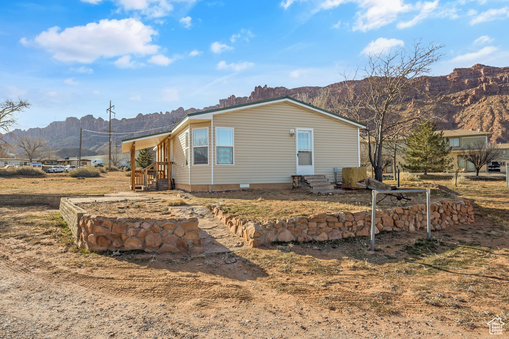View of side of home with a mountain view, entry steps, and crawl space