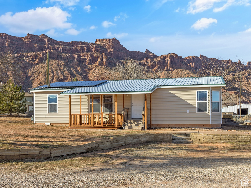 Manufactured / mobile home with a porch, a mountain view, solar panels, and a metal roof