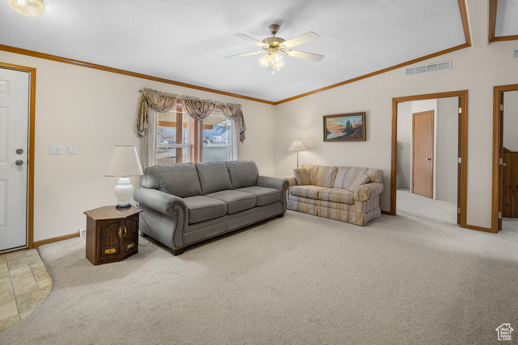 Living area with vaulted ceiling, a ceiling fan, light carpet, and crown molding