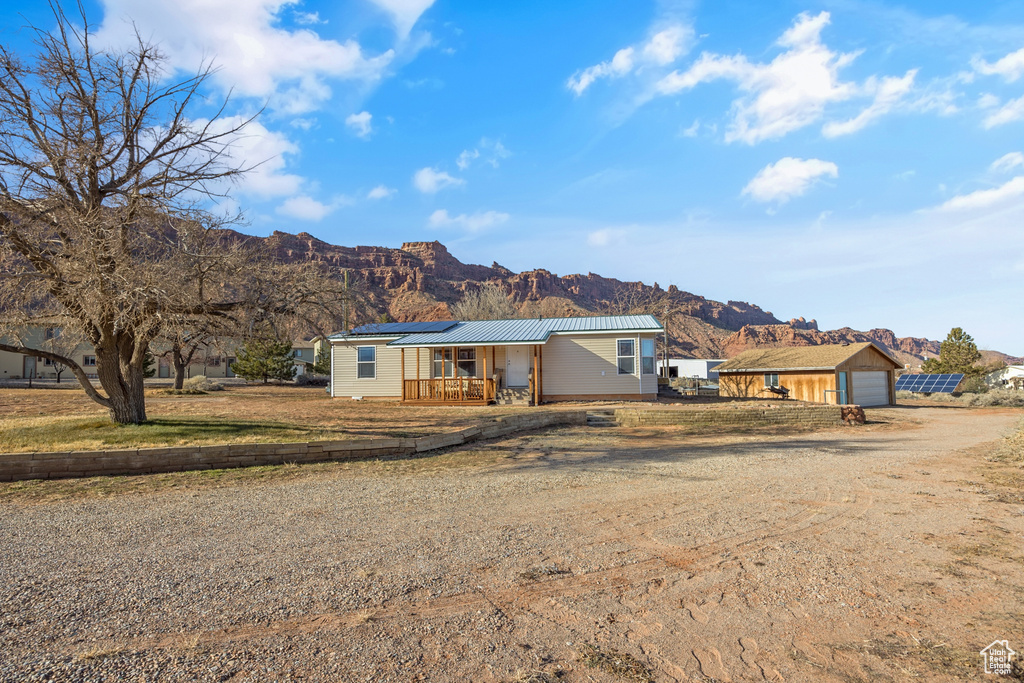 Manufactured / mobile home with dirt driveway, a mountain view, a metal roof, and solar panels