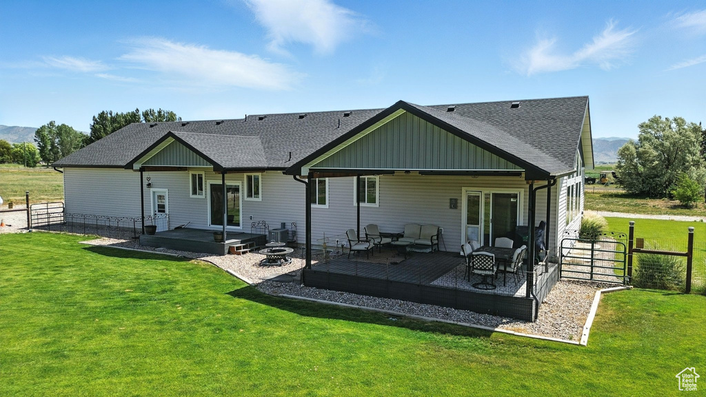 Rear view of property featuring a shingled roof, outdoor lounge area, a deck with mountain view, and board and batten siding