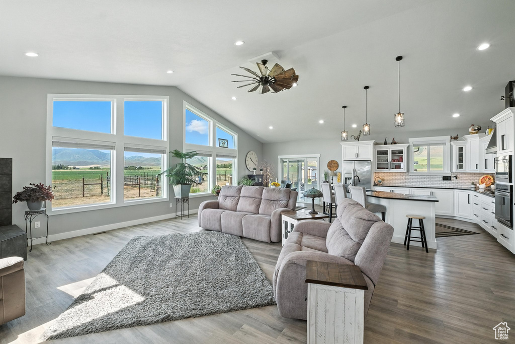 Living room with a ceiling fan, lofted ceiling, recessed lighting, and dark wood-type flooring