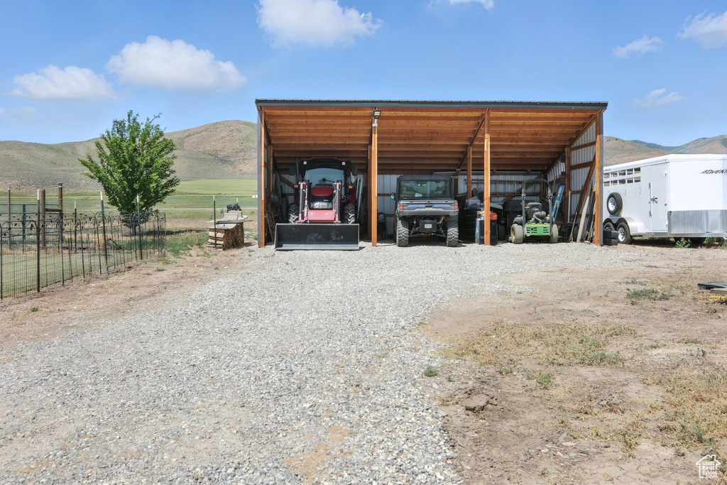 View of outdoor structure featuring a detached carport, a mountain view, and gravel driveway