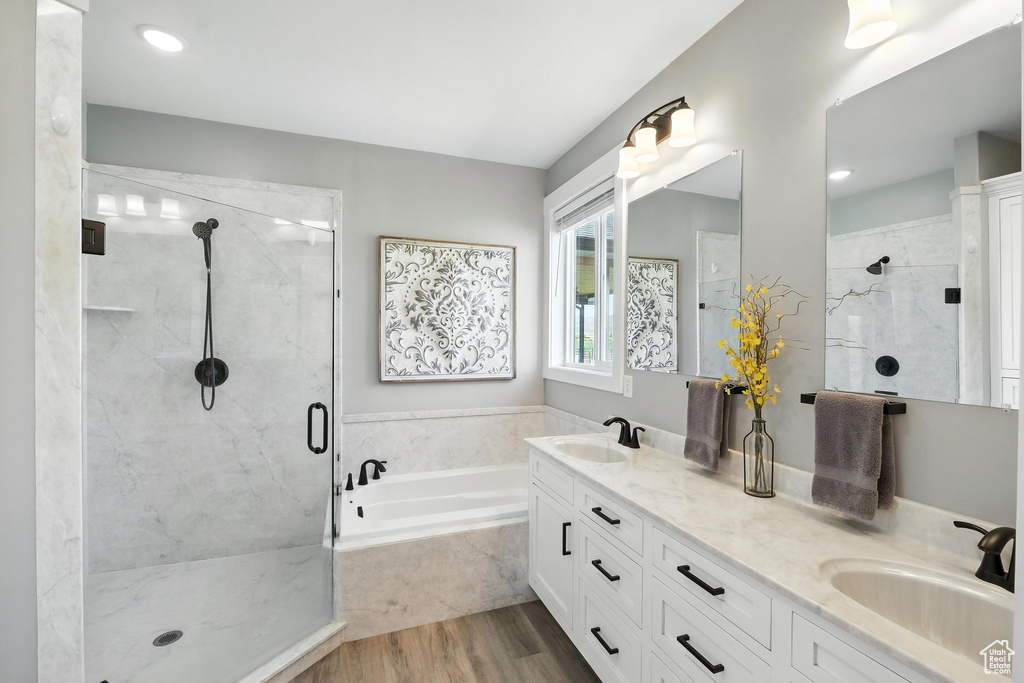 Full bath with a garden tub, a shower stall, double vanity, and wood finished floors
