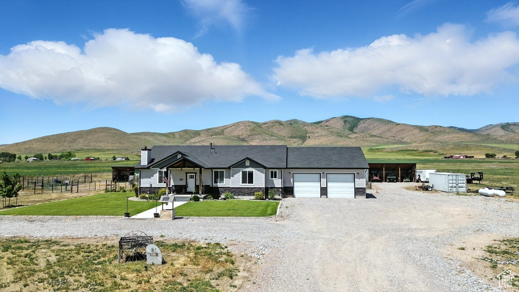 View of front of house featuring a mountain view, a garage, gravel driveway, and stone siding
