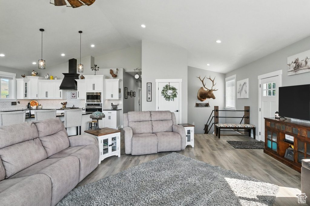Living area with light wood finished floors, recessed lighting, and high vaulted ceiling