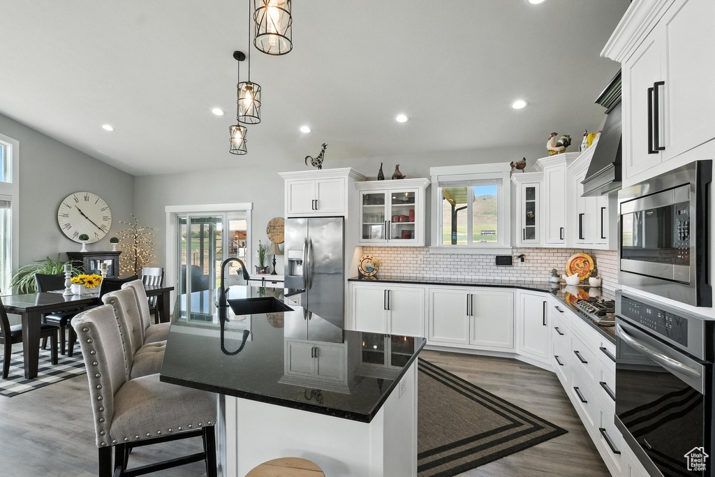 Kitchen featuring stainless steel appliances, recessed lighting, tasteful backsplash, glass insert cabinets, and white cabinetry