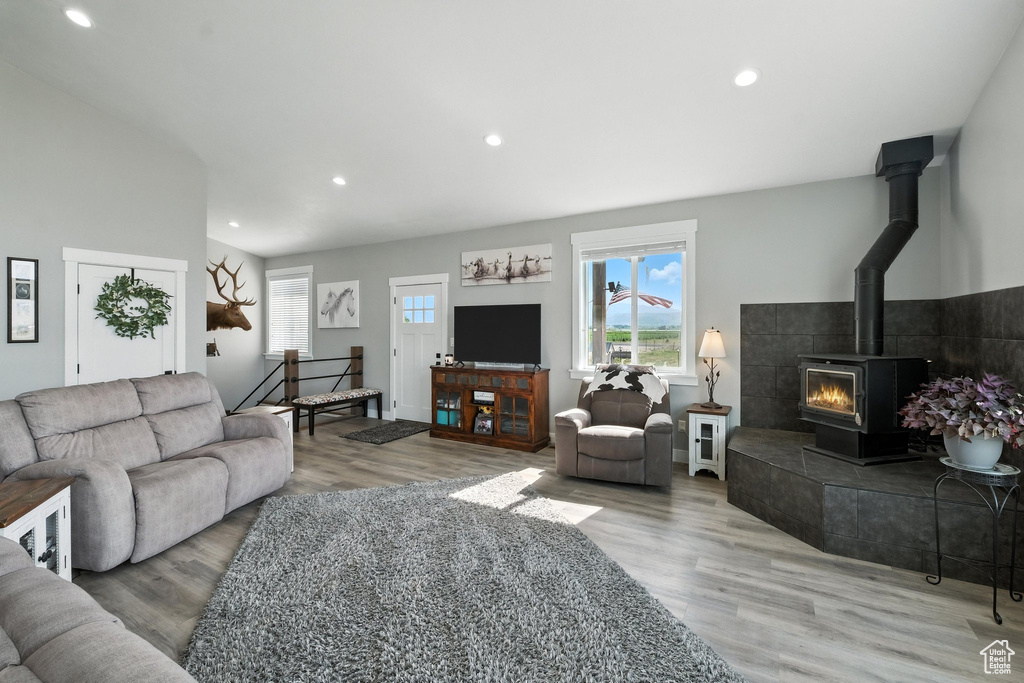 Living area featuring healthy amount of natural light, wood finished floors, recessed lighting, lofted ceiling, and a wood stove