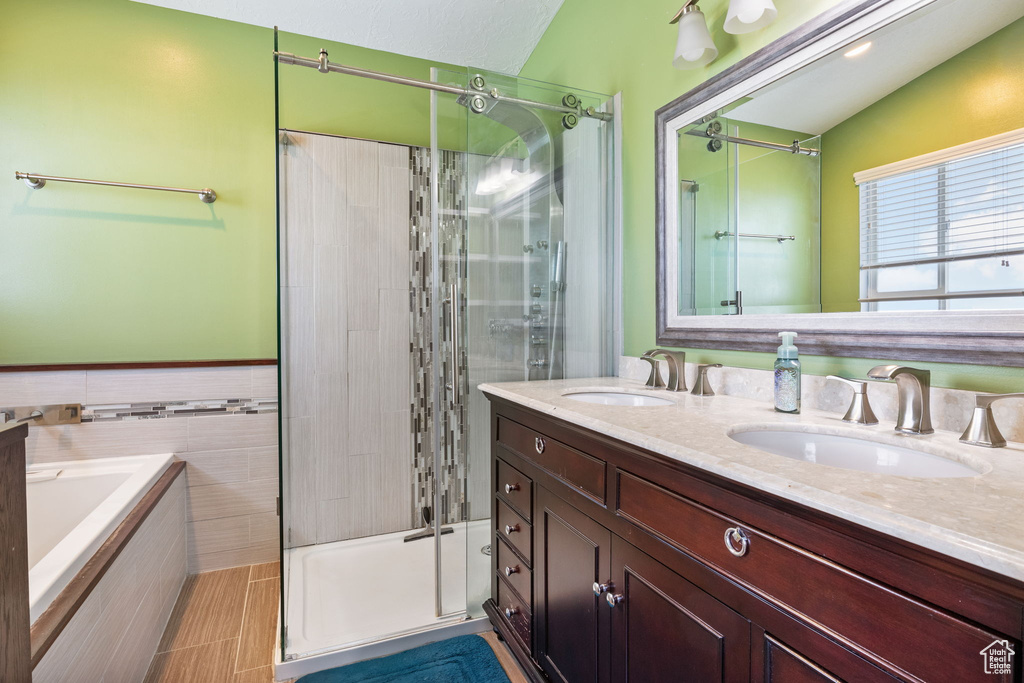 Bathroom with a stall shower, double vanity, a bath, and tile walls
