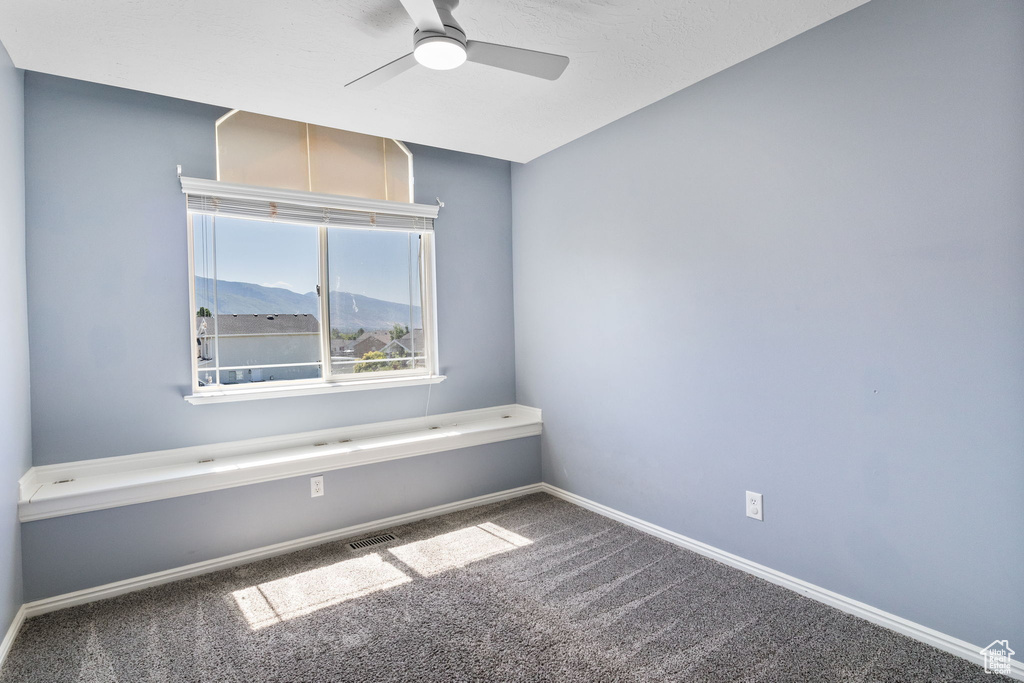 Carpeted spare room with ceiling fan and a mountain view
