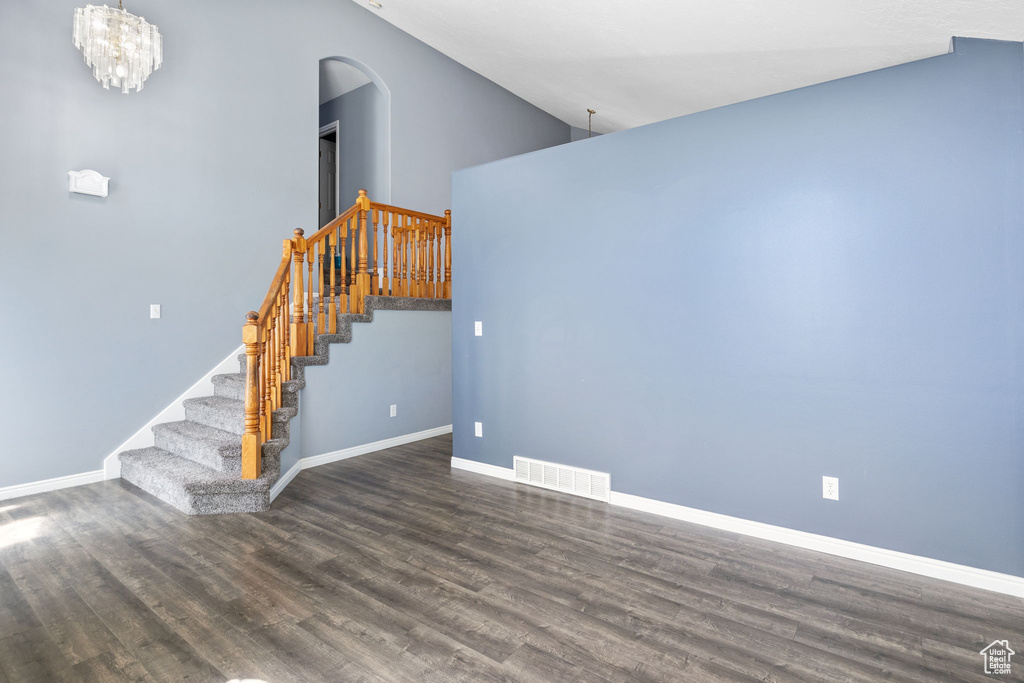 Unfurnished living room with arched walkways, wood finished floors, and stairway