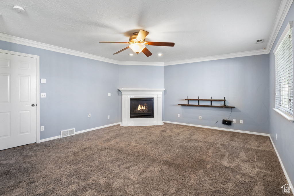 Unfurnished living room with a ceiling fan, carpet flooring, a glass covered fireplace, crown molding, and recessed lighting