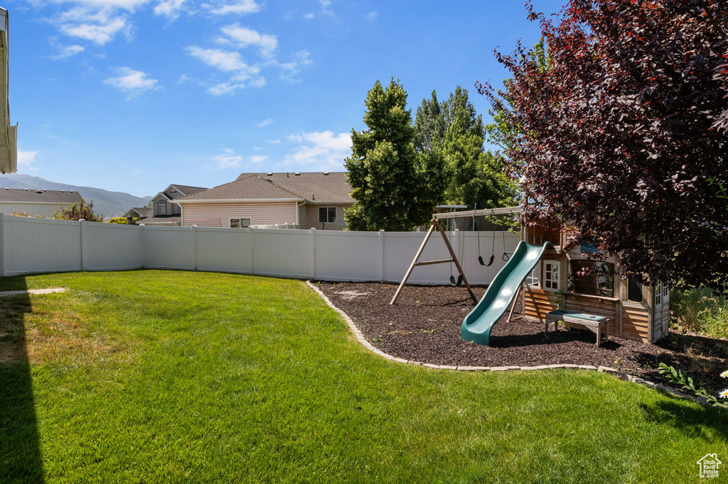 Fenced backyard featuring a playground
